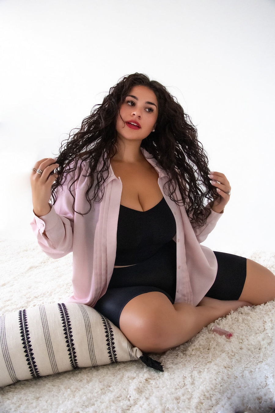 Bridget Haggerty wearing the black EverEase slip short under an open blush shirt, sitting on a cream rug